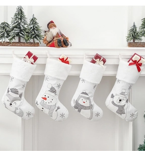 Dettaglio di quattro calze di Natale con motivi animali appese a un caminetto decorato