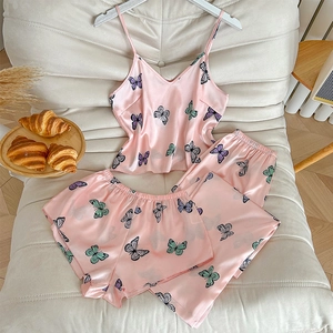 Pink butterfly print 3-piece satin pajama set with camisole and shorts on soft cushion