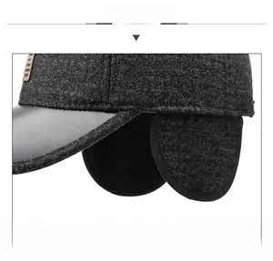 Detailed view of grey tweed winter baseball cap with black faux leather brim and ear flaps