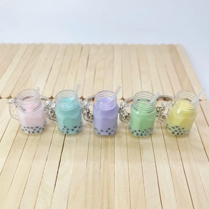 Set of five colorful bubble tea keychains with resin liquid and pearls on wood background