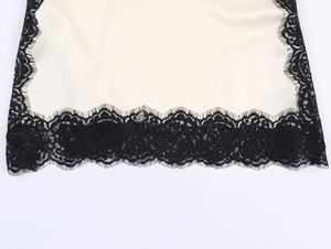 Close-up of elegant ivory satin fabric with delicate black eyelash lace trim detail