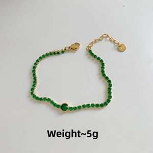 Detailed shot of golden stainless steel bracelet with green zircon stones and 5g weight tag