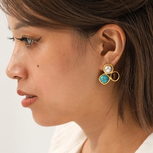 Close-up of pearl and tiger eye stone drop earrings worn by a model in natural light