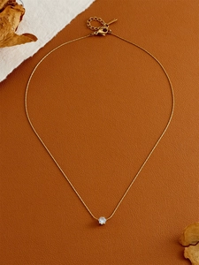 Close-up of minimalist gold necklace with round zircon pendant on leather background