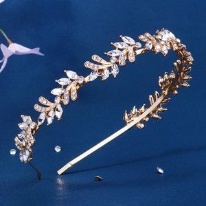 Macro shot of gold leaf branch headband with clear crystals on a dark blue background
