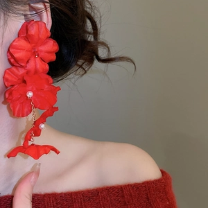 Detailed shot of large red fabric flower earrings with pearls and gold chains
