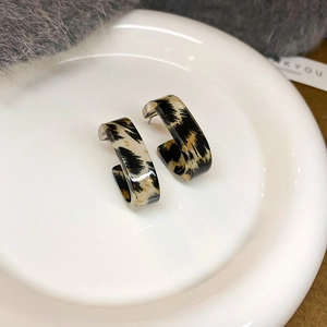 Close-up of leopard print resin C-shaped hoop earrings on a white ceramic tray