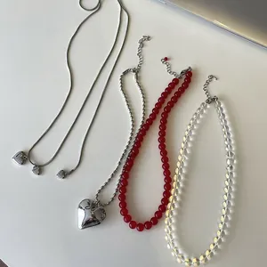Flat lay of four layered necklaces featuring silver heart pendants and colorful beads