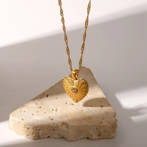 Macro shot of 18K gold plated heart pendant with woven texture and central zircon