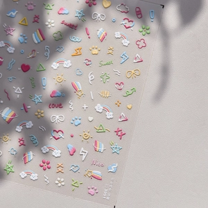 Macro detail of 3D embossed nail stickers featuring colorful rainbows and candy-colored clouds