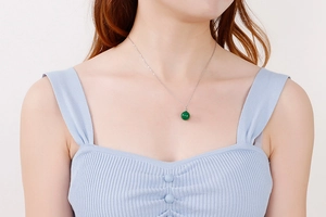 Détail d'un collier en titane argenté avec pendentif en pierre verte sur un mannequin