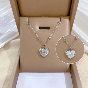 Detail of double-sided heart necklace featuring white mother of pearl and ribbed metal