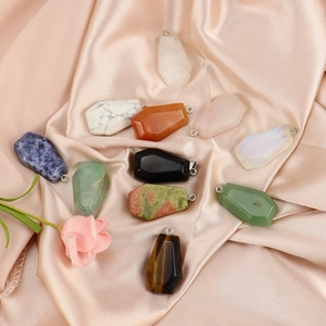 Natural crystal stone mini coffin pendants in various gemstones on elegant satin background