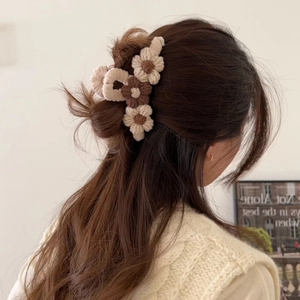Detailed back view of a brown and beige knitted flower hair claw clip on a woman's hair