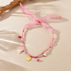 Detailed shot of pink organza ribbon choker with floral, heart, and tassel pendants