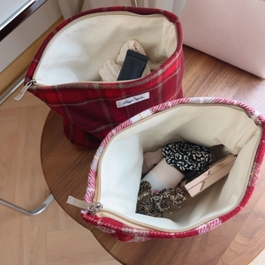 Détail de trousses à maquillage en tweed écossais rouge montrant l'espace intérieur