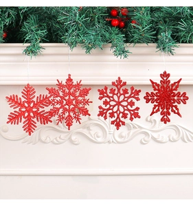 Set of four red glitter snowflake ornaments hanging on a festive decorated mantelpiece