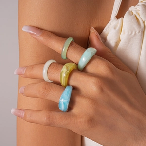 Detailed close-up of acrylic resin rings with marble texture in various colors on hand