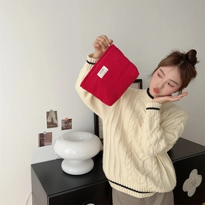 Detail of red waffle fabric pouch with minimalist white label held by a model