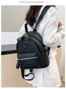 Detail of black backpack with crocodile embossed leather texture and dual zipper compartments