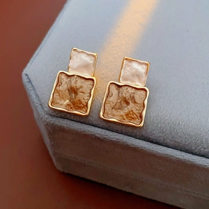 Detail of vintage square drop earrings featuring pearl and brown marble textures