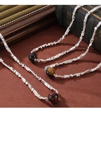 Macro shot of tiger eye stone pendant and silver irregular beads on a beaded necklace