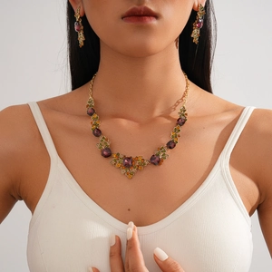 Vintage gold necklace and earring set with purple gems and leaf pattern on model
