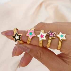 Detail of five gold rings with colorful star enamel patterns on a hand