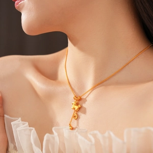 Close-up of gold-plated necklace with a small animal and ancient coin pendant on model
