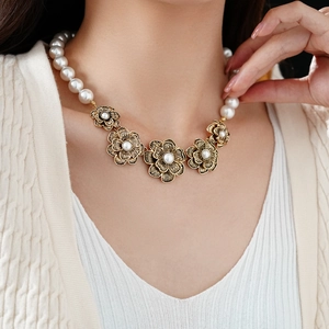 Detail of vintage necklace with white pearls and golden hollow flowers on a model