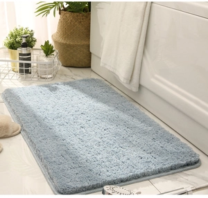 Detail view of light blue microfiber bath mat on tiled floor next to a white bathtub