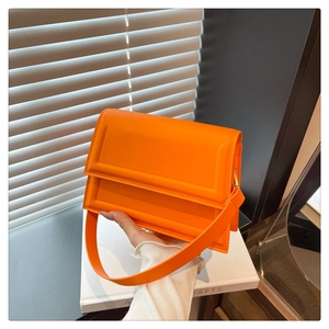 Close-up of orange minimalist crossbody bag featuring 3D geometric textured PU leather