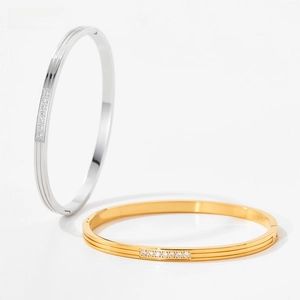 Detail view of gold and silver hinged bangles with white zircon stones and sleek metal finish
