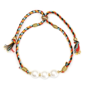 Detail of woven rope bracelet with three white pearls and golden beads on white backdrop