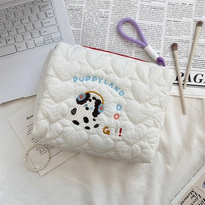 Detail of white quilted cosmetic bag with heart stitching and puppy embroidery