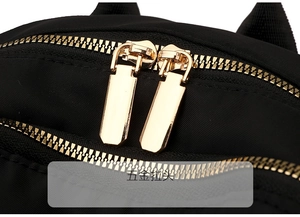 Detail shot of smooth golden metal zippers on a high-quality black nylon travel backpack