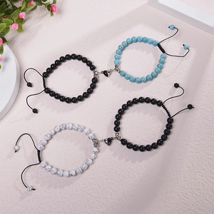 Magnetic heart couples bracelets with matte black and natural stone beads on a beige background