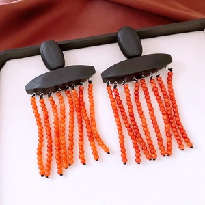 Detailed close-up of ethnic style beaded fringe earrings with black geometric wooden studs