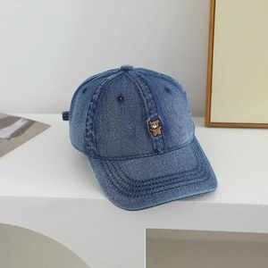 Close-up of brown bear embroidery on a dark blue denim baseball cap for kids