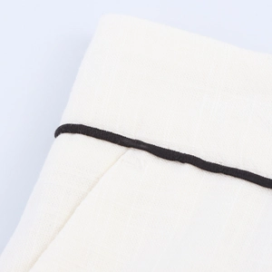 Macro shot of white cotton-linen fabric featuring contrasting black piping details