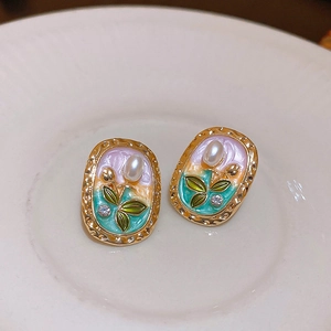 Detailed macro view of vintage floral enamel earrings with pearls and crystals