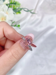 Detailed close-up of a pink oval gemstone ring with micro-paved diamonds on a silver band