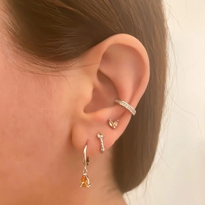 Close-up of gold plated earring set with yellow pear gems and studs on a model