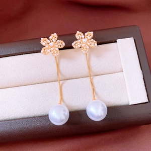Detailed macro view of 18k gold flower earrings with zircon petals and white pearls