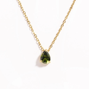 Close-up of pear-cut green zircon pendant with four-prong setting on golden chain