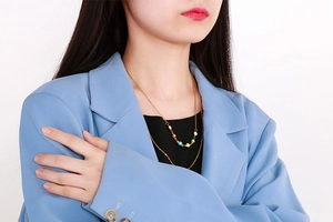 Detail of gold double-layered necklace featuring colorful enamel evil eye beads on a model