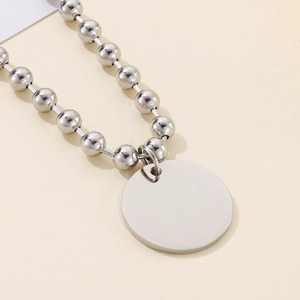 Gros plan détaillé d'un collier à billes argenté avec un pendentif disque rond poli
