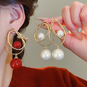 Détails de boucles d'oreilles en fil de métal doré avec perles blanches et rouges élégantes
