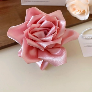 Gros plan d'une pince à cheveux rose satiné avec pétales multicouches et lustre perlé