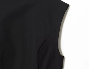 Detail of shoulder seam and armhole tailoring on a black woven vacation dress
